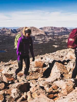 Two women hiking uphill through rocky terrain.