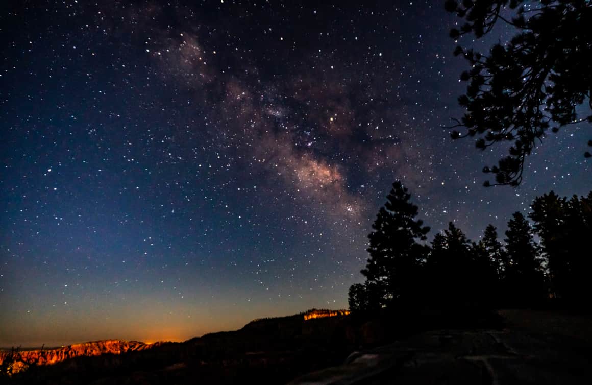 Stargazing from the Rim Trail just before sunrise. The rising sun illuminates the canyon and hoodoos from below the horizon.