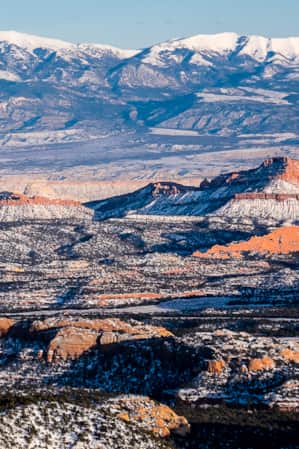 A landscape of rocky formations with sparse vegetation, all covered in snow.