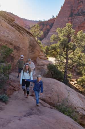 A family hiking in the shade through a red rock landscape.
