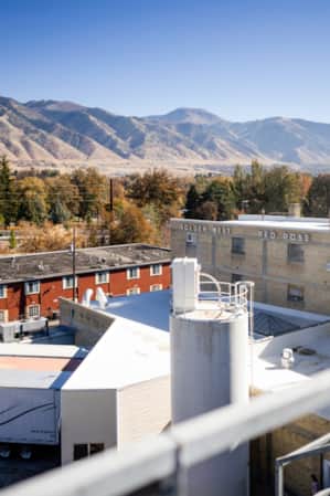 The view from the top of a building overlooking warehouses, with mountains visible in the distant backdrop.