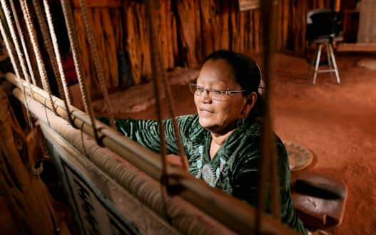 A Navajo woman weaves something of beauty in Monument Valley.