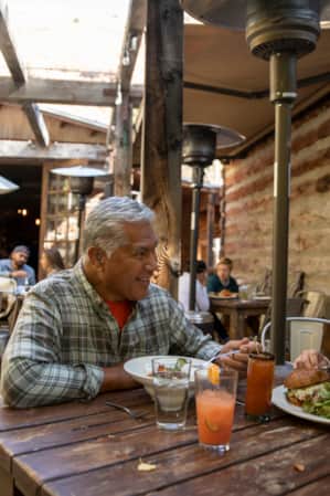 A man and a woman eating at a rustic restaurant patio with a cozy setting.