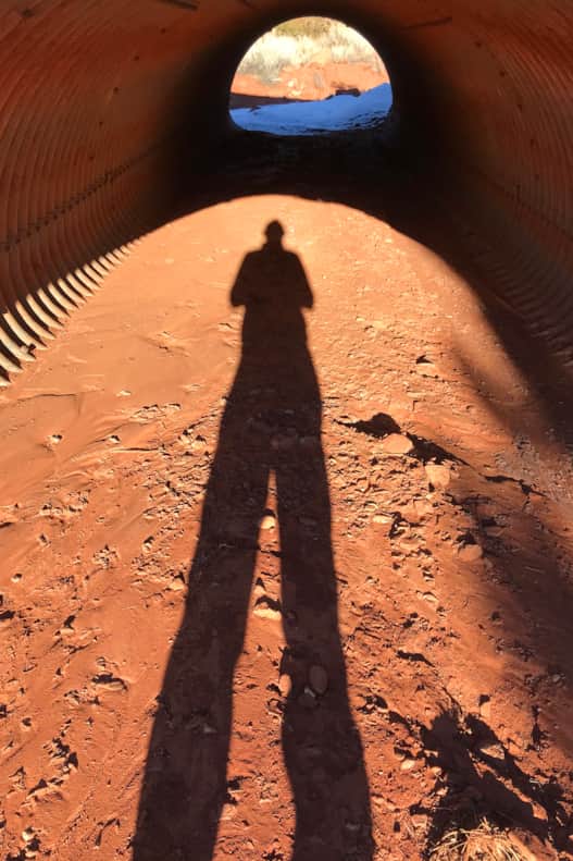 The author stops briefly at the entrance to a culvert, flattened by time and the weight of a million cars and trucks.