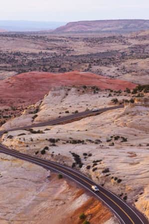 Expansive view of Utah's red rock landscape with Scenic Byway 12 winding through the terrain and two cars on the road.