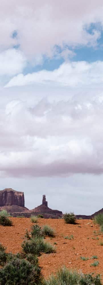 Two people hiking on a cloudy day along a path leading towards large monuments in the distance.
