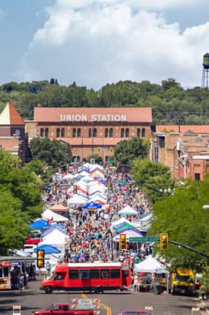 An overhead view of Ogden's downtown main street, bustling with crowds of people walking and exploring market tents set up along the road.