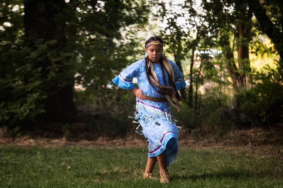 A young girl performs a Shoshone dance in a traditional jingle dress.